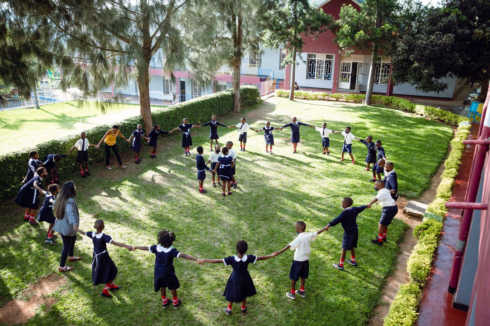 Schoolchildren holding hands in a circle on a lawn