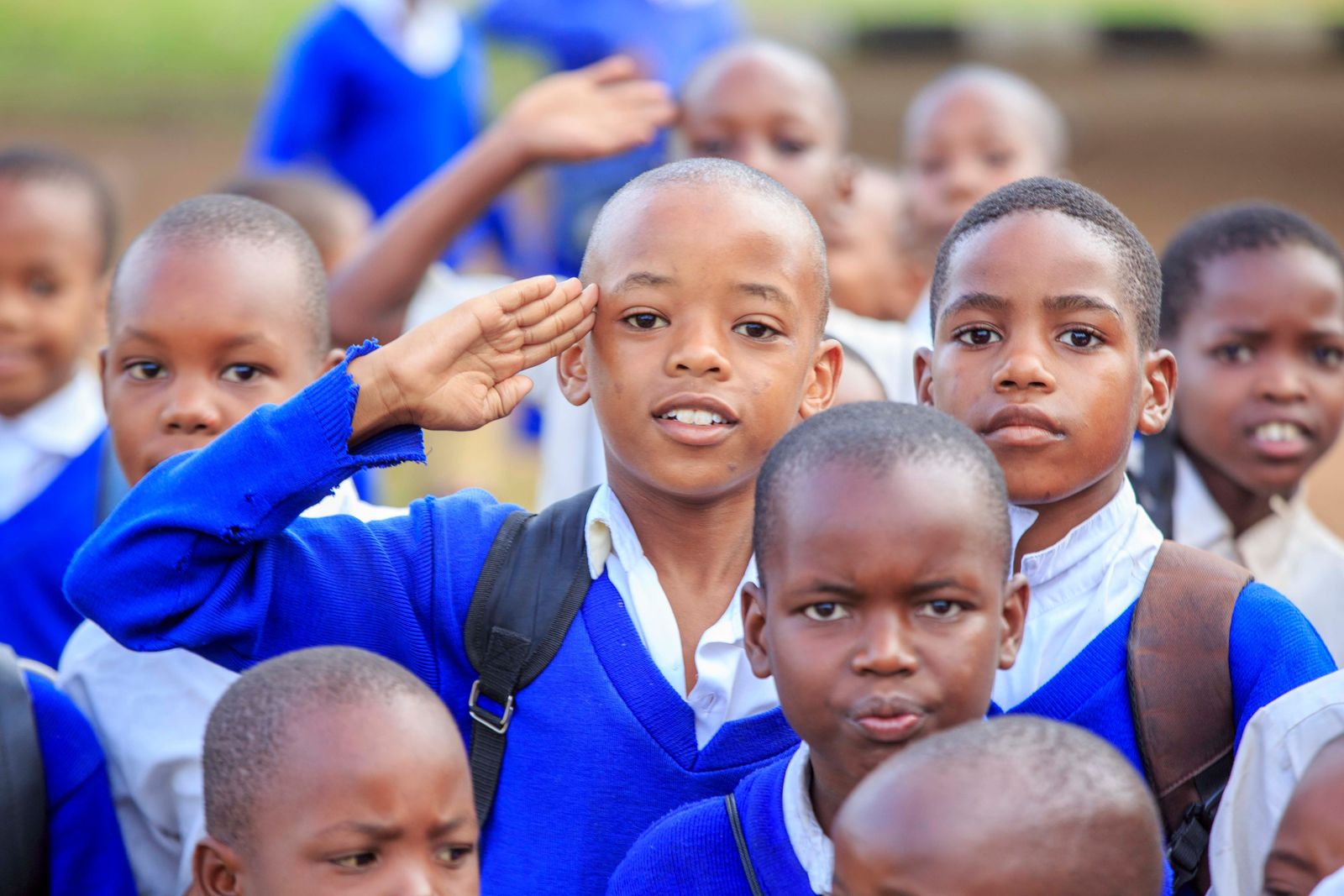 Schoolchildren in blue uniforms, one giving a salute